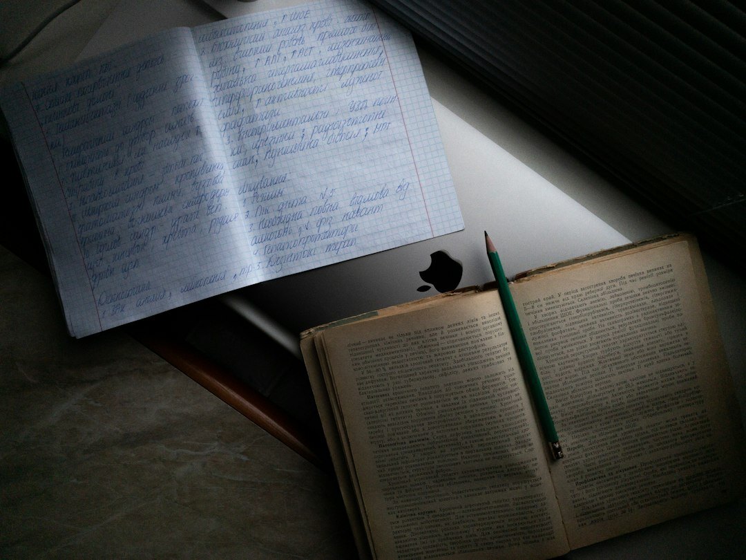 Reporter writing notes in a notebook next to a laptop